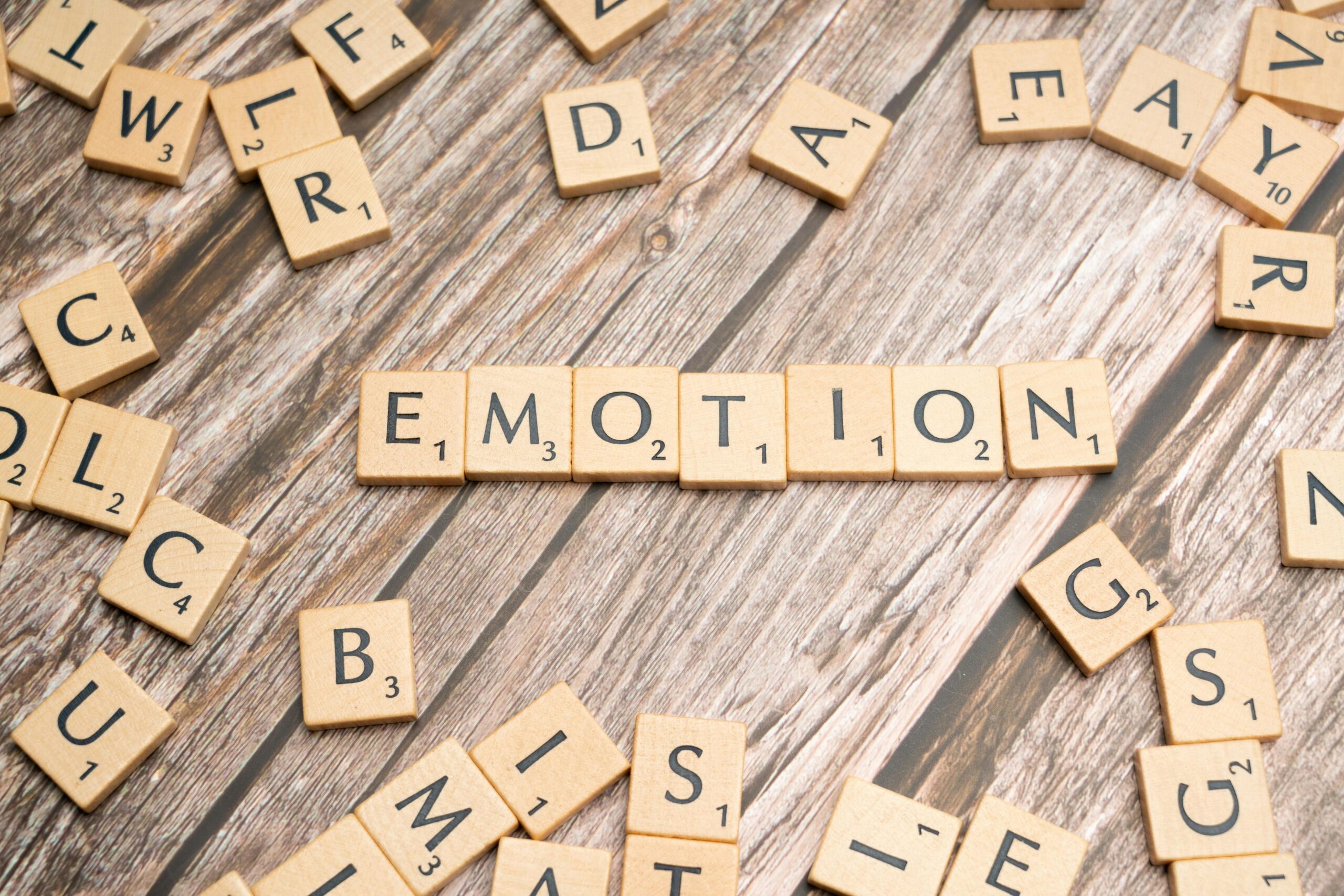 Scrabble tiles forming the word emotion on a wooden background.