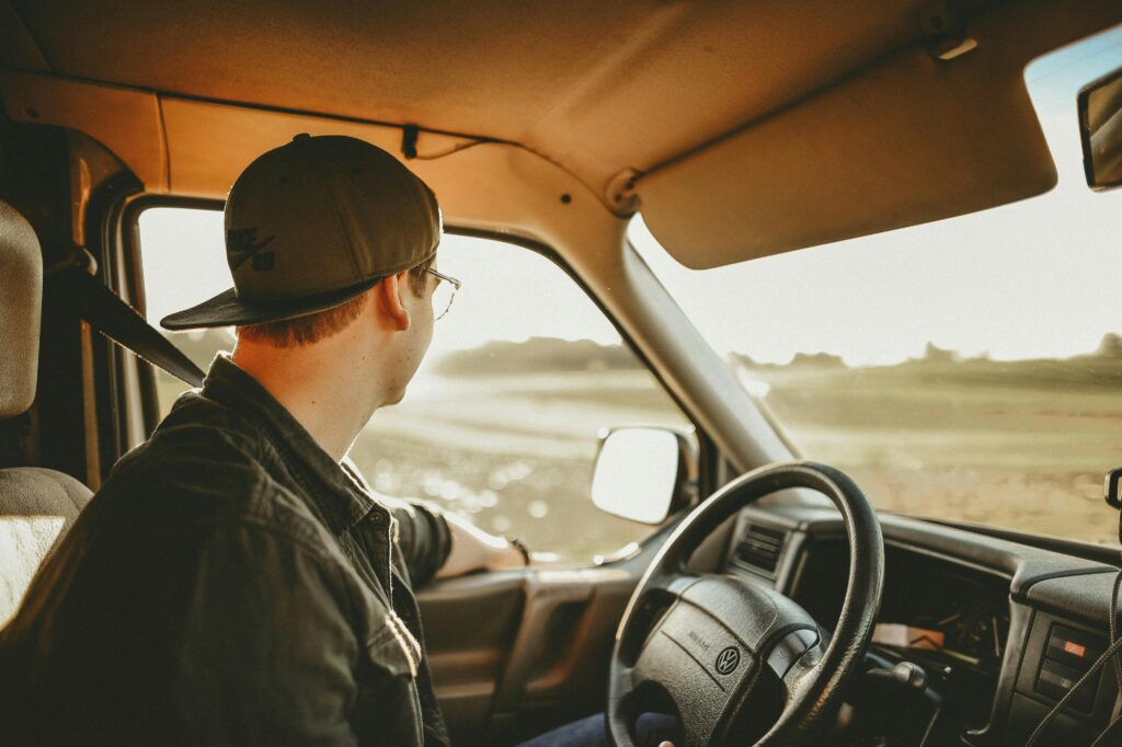 A man enjoys a relaxed drive through the countryside on a sunny day, looking out onto the scenery.