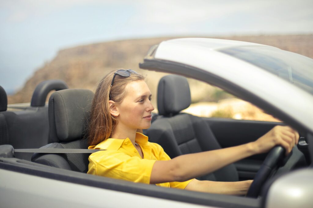 A young woman enjoys driving a convertible on a sunny day in Malta.